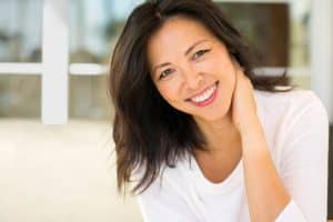 Asian woman maintains a glowing appearance while questioning whether further rejuvenation is necessary.