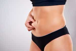 Woman with abdominal fat considering tummy tuck options.